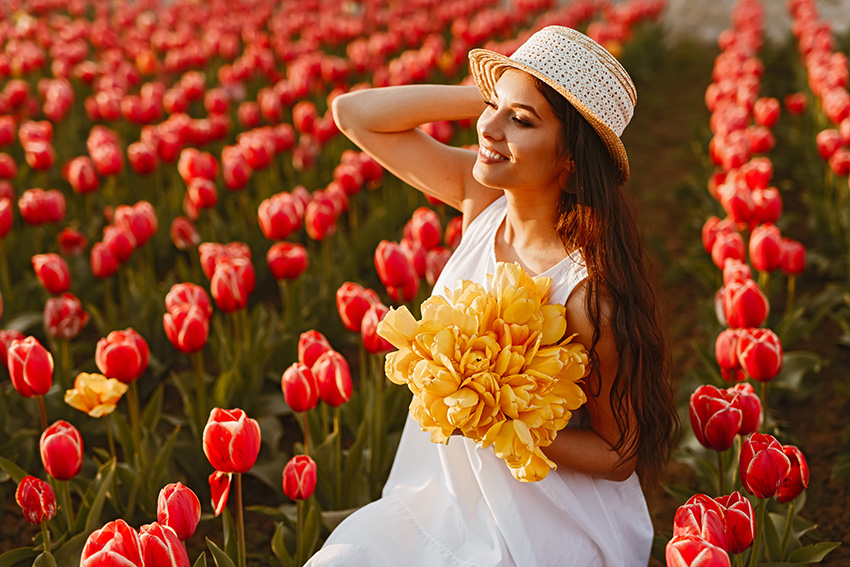 joyful woman with bouquet sitting on tulips field 2022 11 12 13 12 18 utc