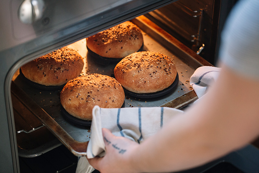 woman taking homemade vegan burger rolls out of ov 2022 12 16 22 05 57 utc